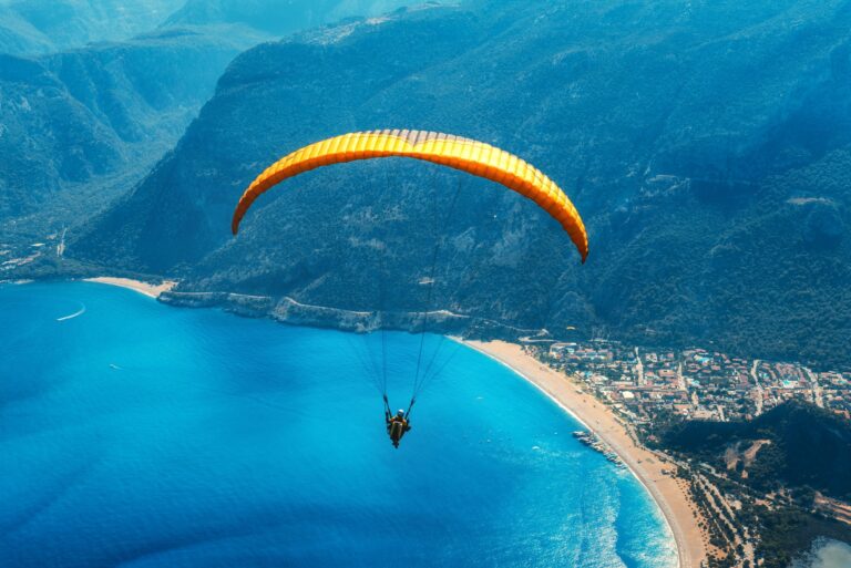 paraglider-tandem-flying-over-the-sea-with-blue-water-and-mountains.jpg